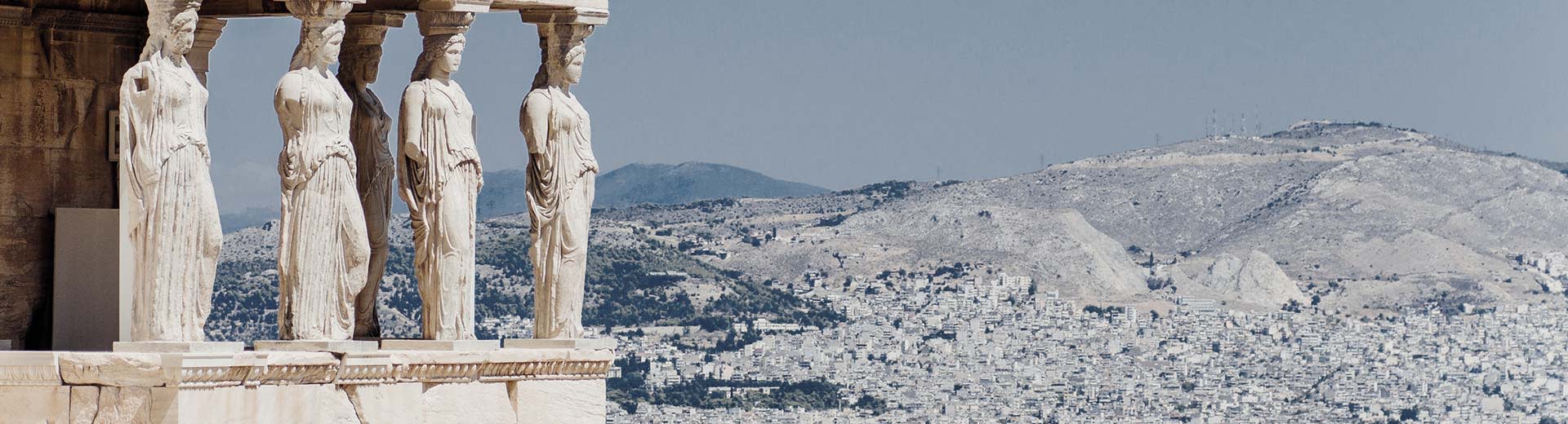Caryatids of the Erechtheion in Athens with mountains in the background.