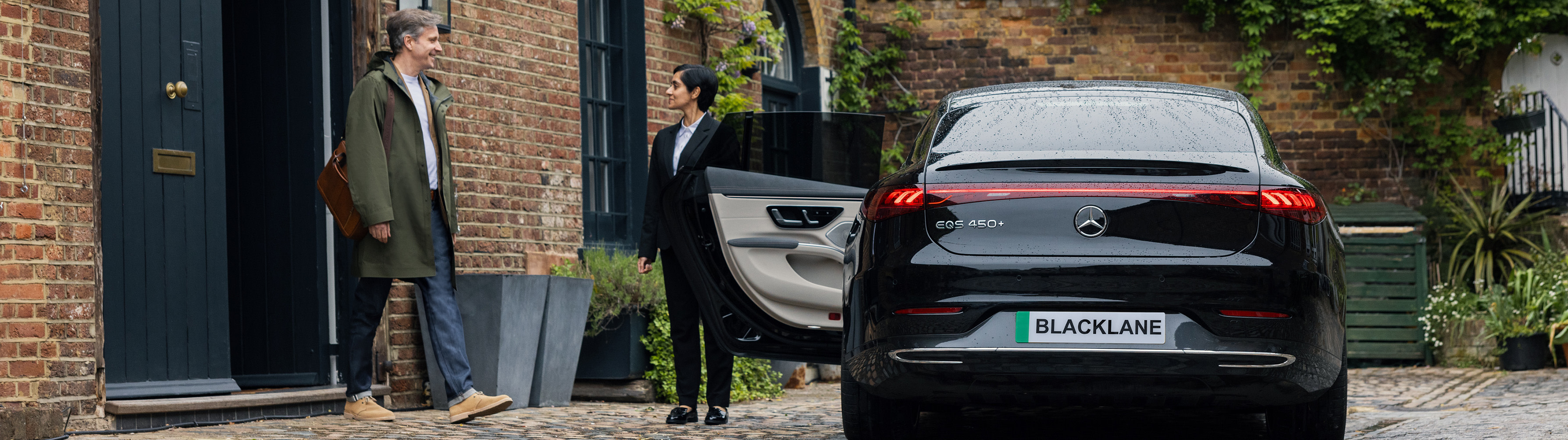 Blacklane chauffeur opening the door of a Mercedes EQS to let in a guest.