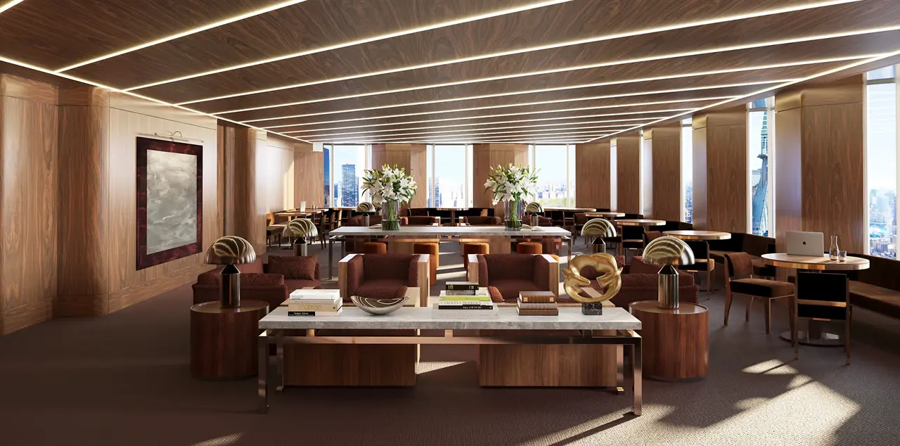One of the ornate coworking rooms in the Colette New York private members club, with a marble desk and brass reading lamps in a room with a modern paneled ceiling.