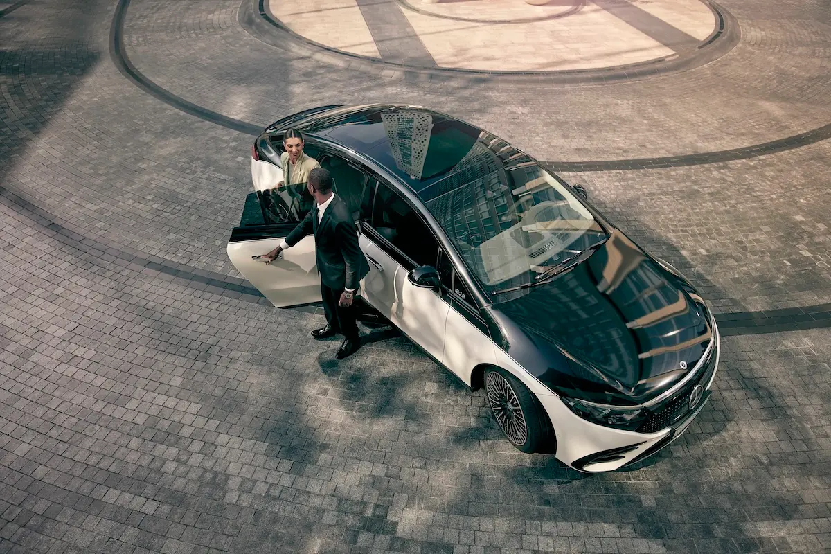 A chauffeur opens the door of a Blacklane limo and a woman in a headscarf gets in.