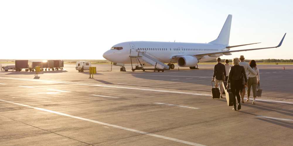 Passengers walking to a jet plane at sunset.