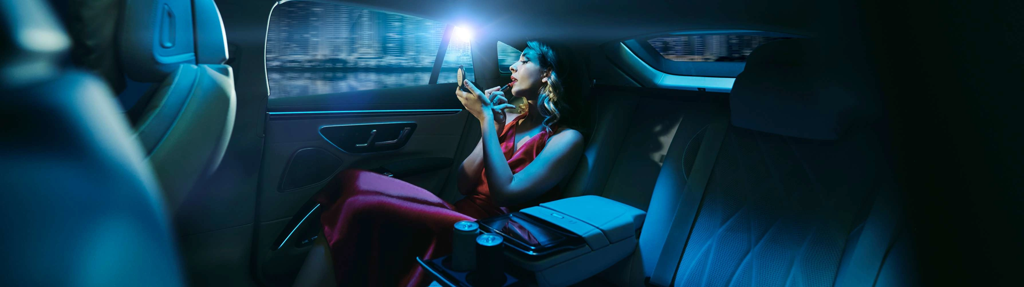 A glamorous woman sits in the back seat of a Blacklane limo on the way to a concert, topping up her makeup.