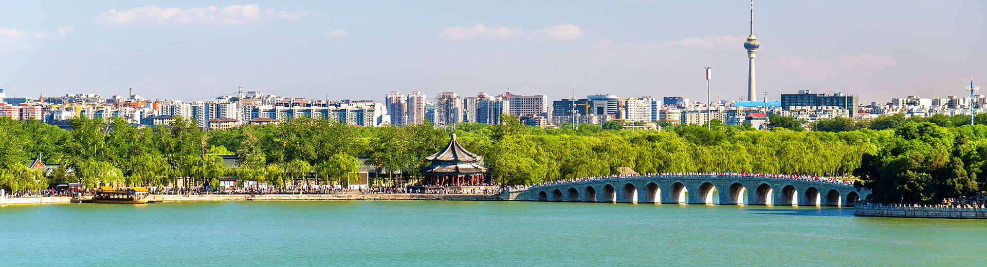 Beautiful blue water passes underneath a bridge, with the skyline of Kunming looming in the background.