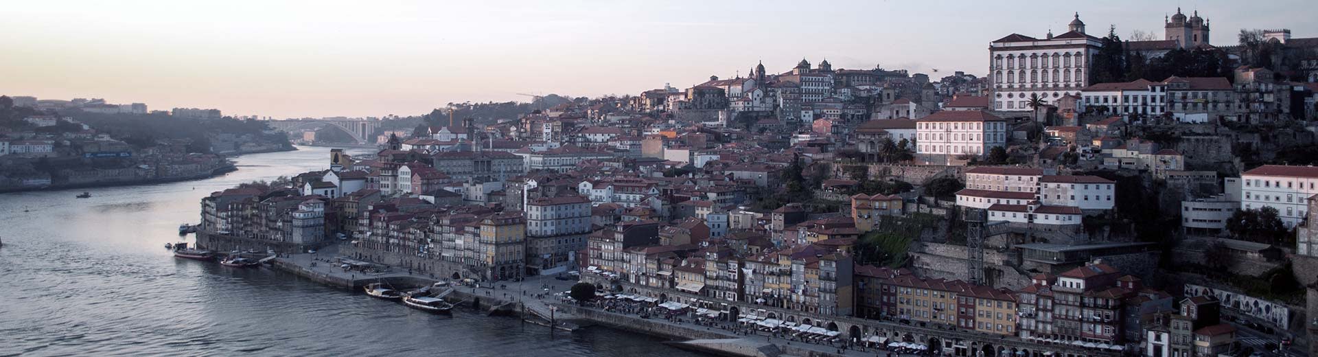 The beautiful city of Porto, with historic buildings set against a grey sky and flowing river.