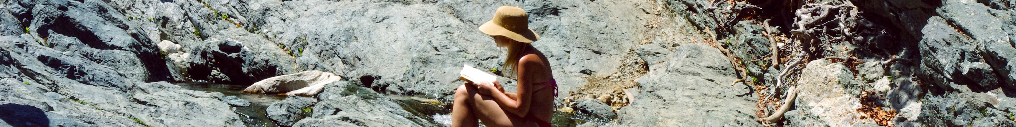 A woman reading a book on a nature rock