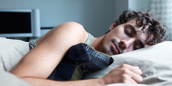 A man with brown hair sleeping in a bed