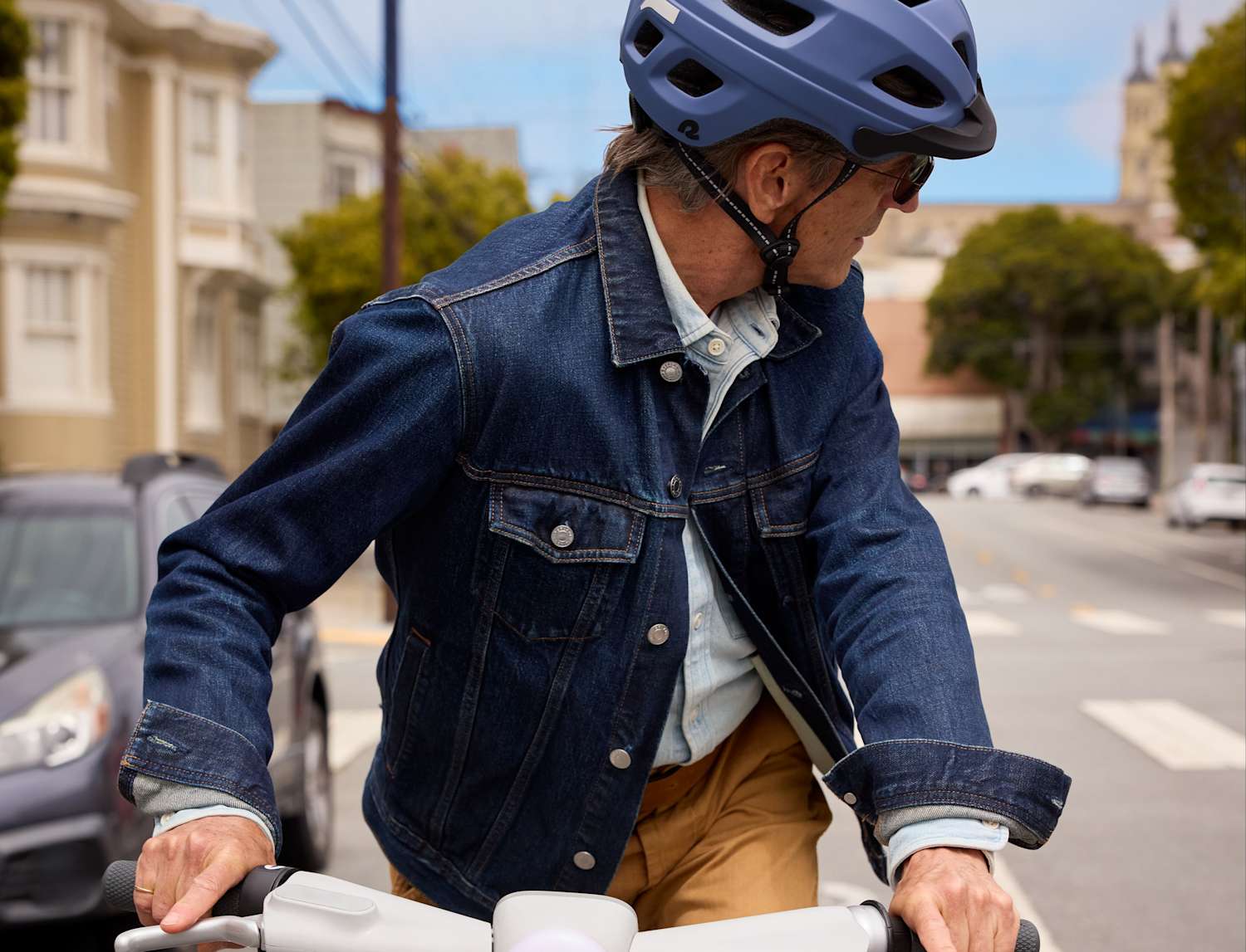 A man wearing business attire rides a classic bike.