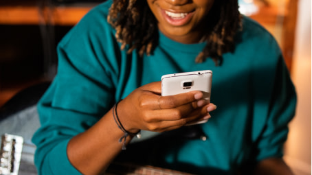 Woman holds a mobile phone in her hand managing her car insurance coverage