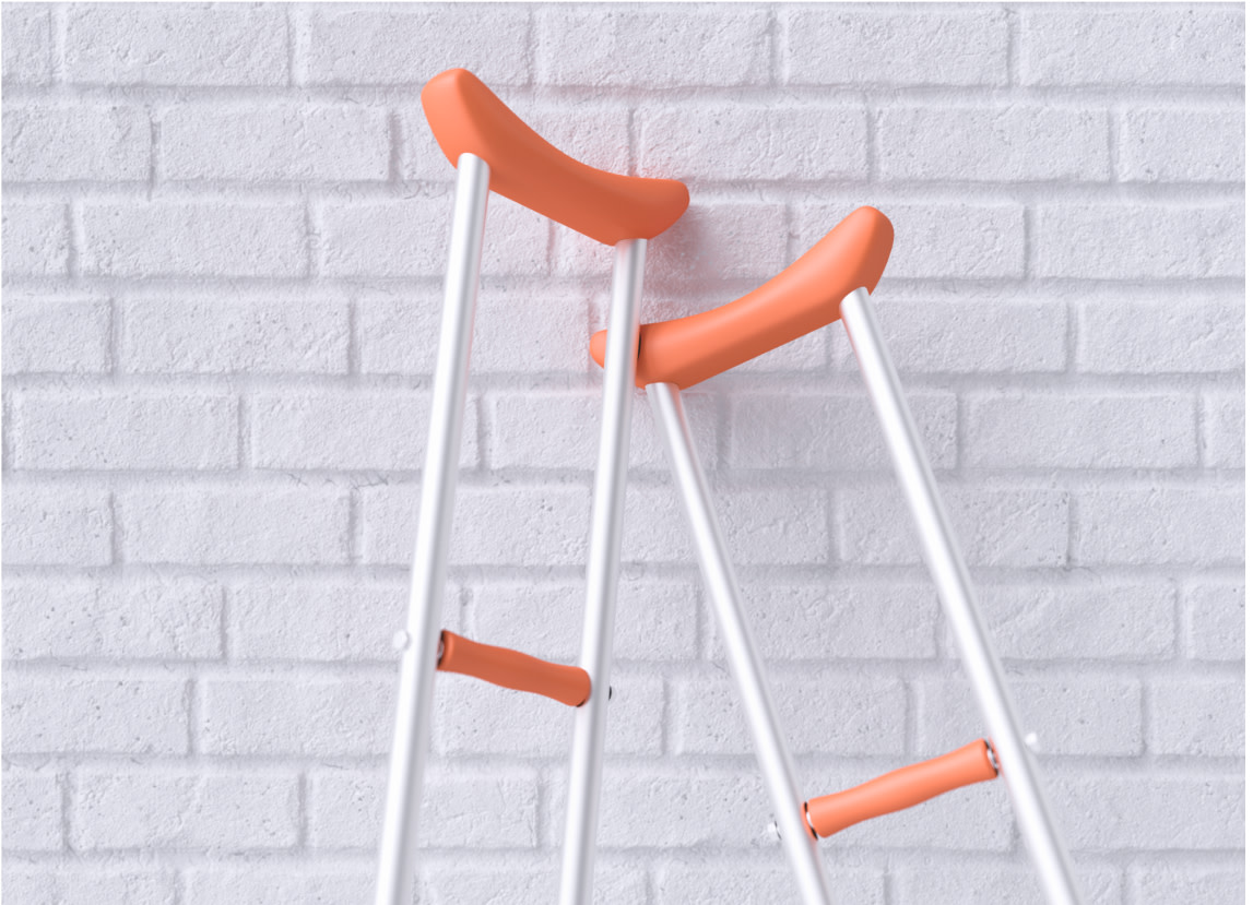 Orange crutches leaning against a white brick wall