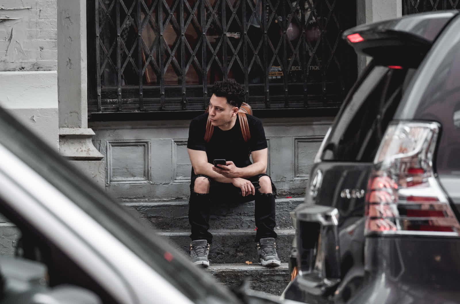 A person sits on a city curb waiting for roadside assistance