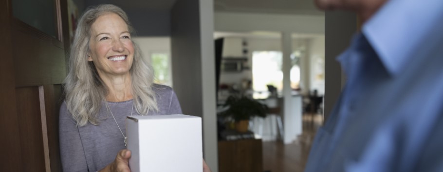 Over 50 female smiles at the postman after being handed their online order after reading about tech life hacks
