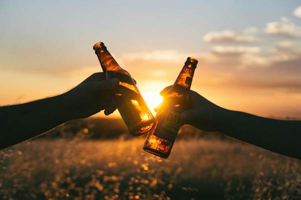 cheers-ing two beers at sunset