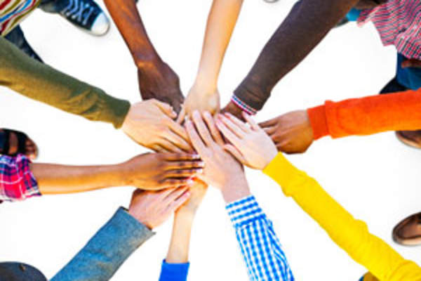 racially diverse circle of people stretches one hand into center