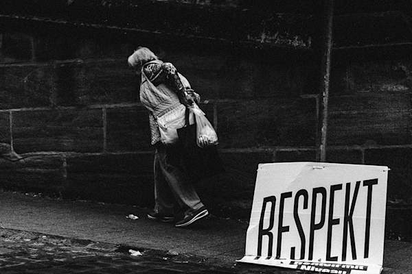 Woman walking past sign that reads "RESPEKT"