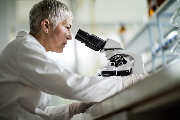 Below view of female scientist looking through a microscope