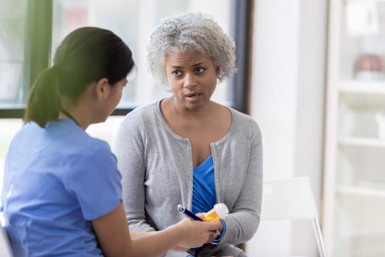 Young nurse handing prescription to senior woman
