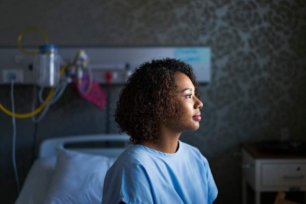 Side view of African American female patient sitting at hospital