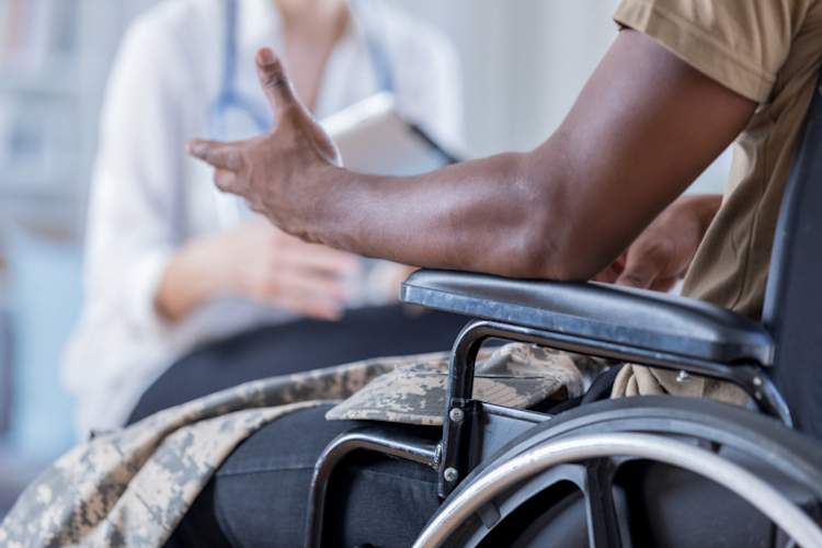 man in wheelchair gesturing towards doctor