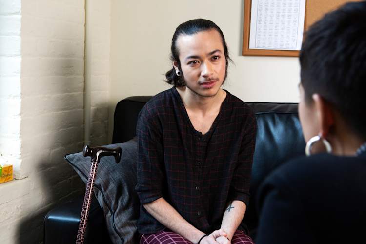 A genderqueer person sitting on a therapist's couch, listening