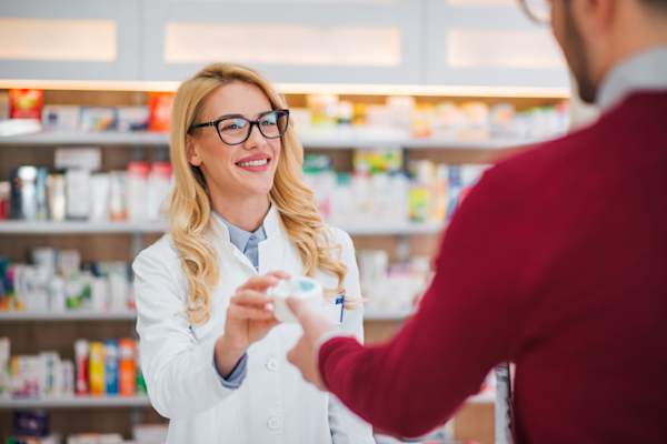 pharmacist handing man prescription