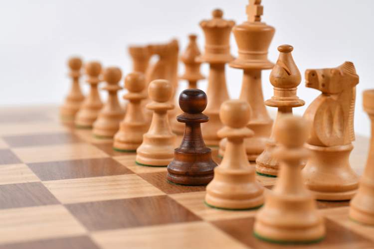 chess pieces on chessboard, one pawn is different than the rest of the pieces