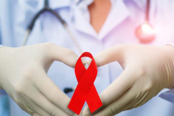 A doctor forming hands into a heart with a red ribbon
