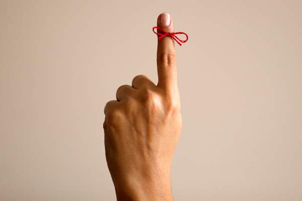 Red ribbon tied around a finger.