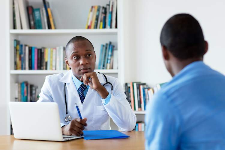 Black man talking with his doctor in office.