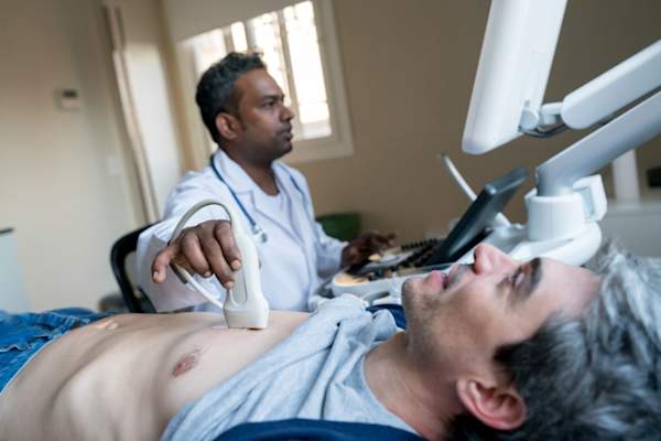 doctor doing a heart ultrasound to a middle aged male patient