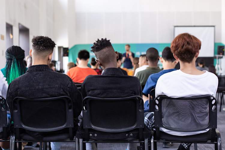 three students sitting in the back of the classroom