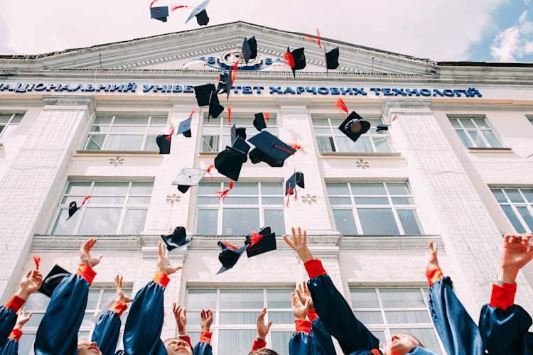 Graduates throwing graduation caps, motorboards in the air.