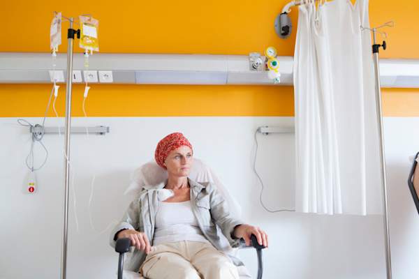 woman in headscarf receiving chemotherapy in yellow room
