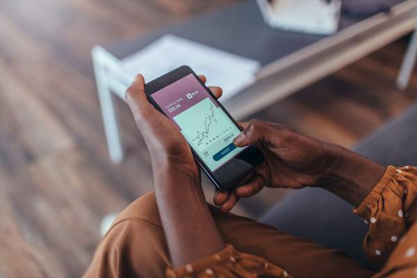 woman holding smart phone with graph on screen