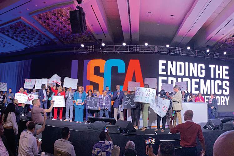 HIV community members protest the use of molecular surveillance onstage at the 2019 United States Conference on AIDS