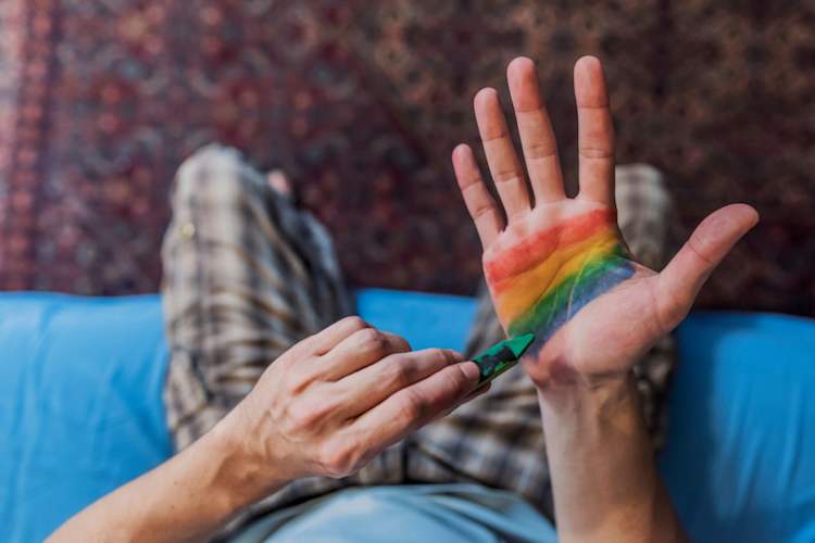 Man painting rainbow flag on his hand
