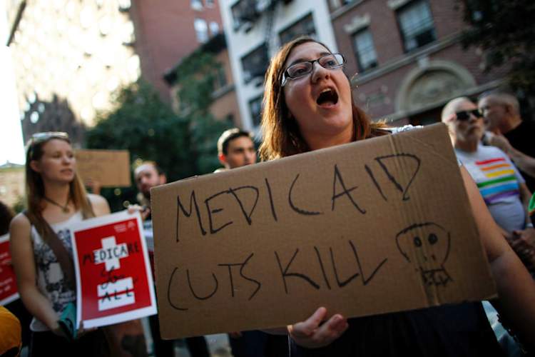woman at rally with sign reading "MEDICAID CUTS KILL"