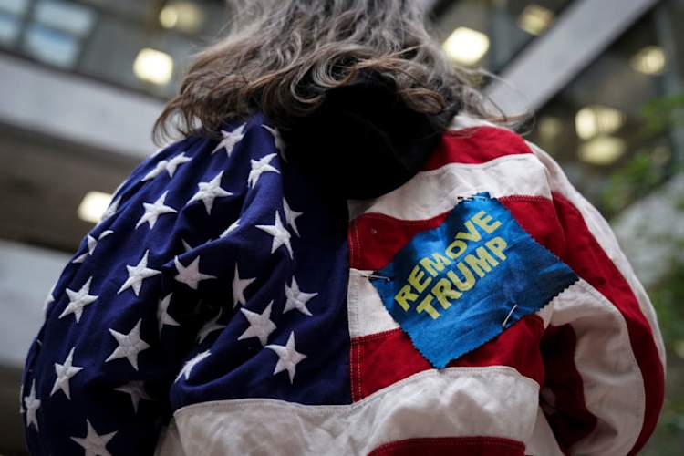 person at political rally wearing American flag and patch that reads "REMOVE TRUMP"