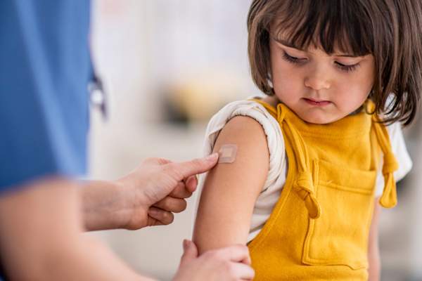 doctor is applying a bandage to her patient after giving her a vaccination
