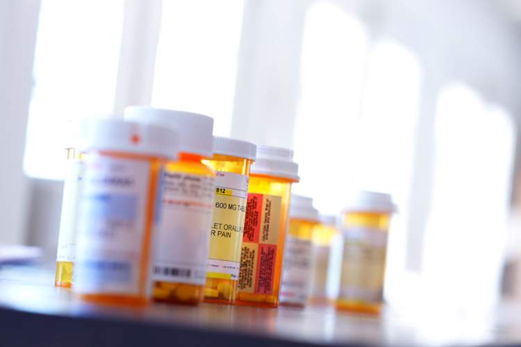 Several Medication Pill Bottles On Table In Front Of Windows