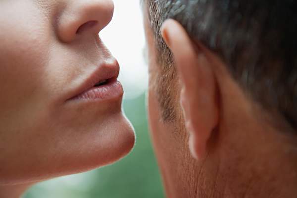 Woman whispering into man's ear