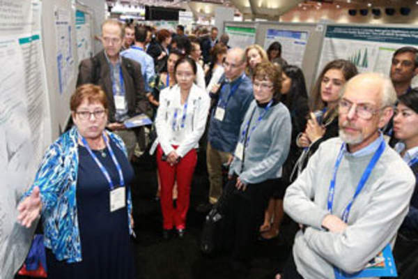 Attendees discuss a poster presentation at IDWeek 2017 (Credit: Infectious Diseases Society of America)