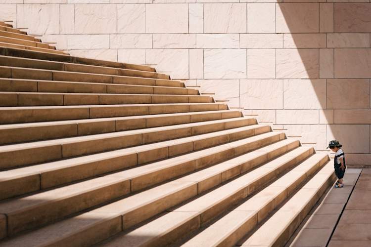 Small boy looking at giant staircase - facing obstacle concept