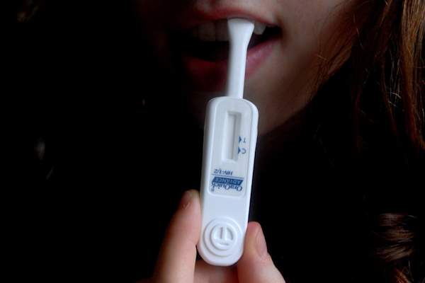 A woman demonstrates the use of the OraQuick rapid HIV test