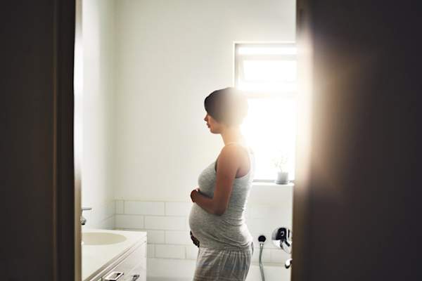 pregnant woman looking in mirror