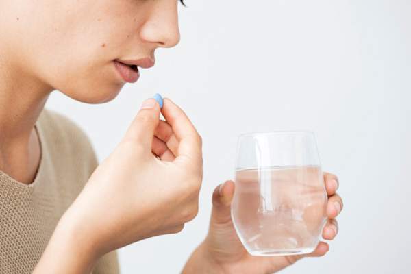 young woman taking blue pill