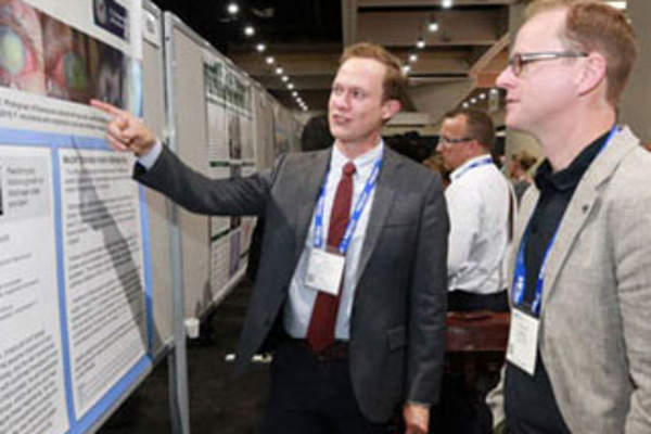 Attendees discuss a poster presentation at IDWeek 2017 (Credit: Infectious Diseases Society of America)
