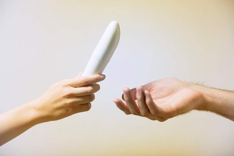 Close up of woman's hand, handing a man's hand a vibrator