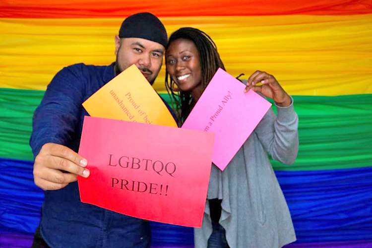 Tone Vai and Kamailia Williams of Instituto Familiar de la Raza hold LGBTQ pride signs during Give OUT Day 2017