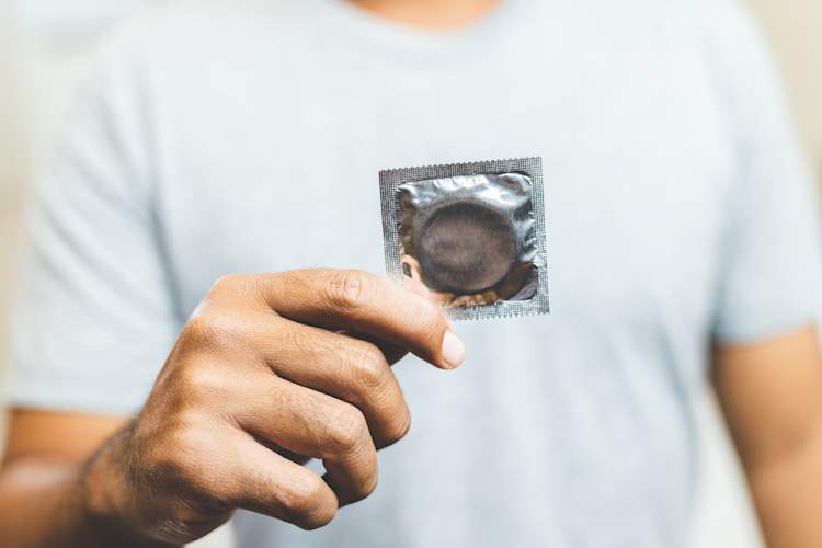 Man holding a wrapped condom.