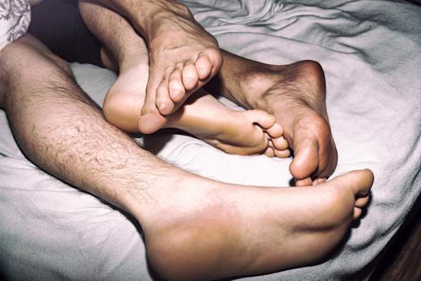 men's feet tangled in bed